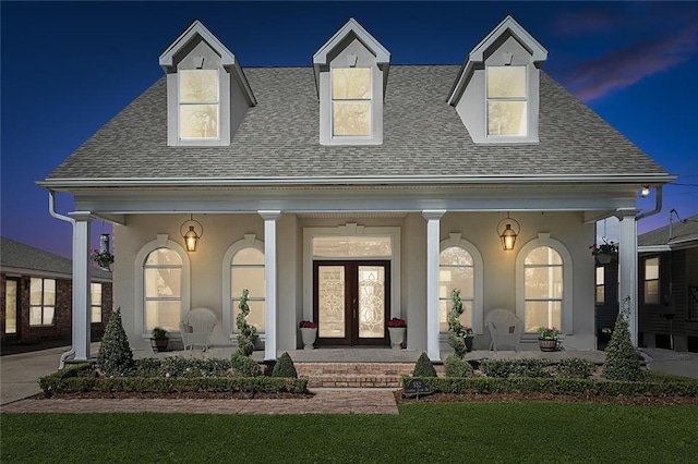 view of front facade with french doors, roof with shingles, a porch, and stucco siding