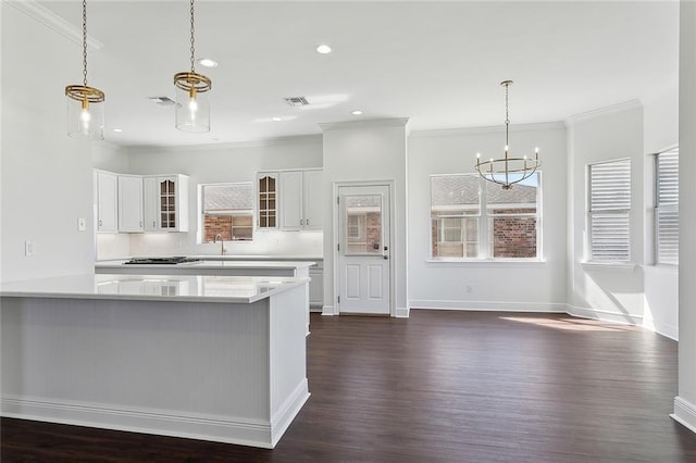 kitchen featuring glass insert cabinets, decorative light fixtures, light countertops, a notable chandelier, and white cabinetry