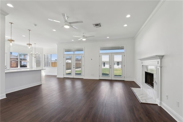 unfurnished living room featuring visible vents, a premium fireplace, dark wood-style flooring, crown molding, and ceiling fan with notable chandelier