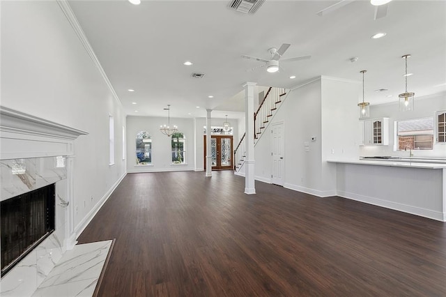 unfurnished living room with visible vents, ceiling fan with notable chandelier, a fireplace, and ornamental molding