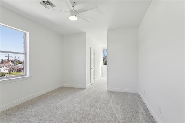 carpeted empty room with visible vents, baseboards, and ceiling fan