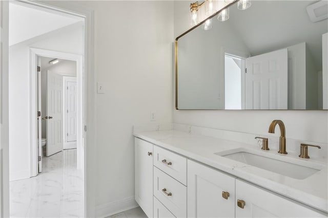 bathroom with vanity, baseboards, vaulted ceiling, toilet, and marble finish floor