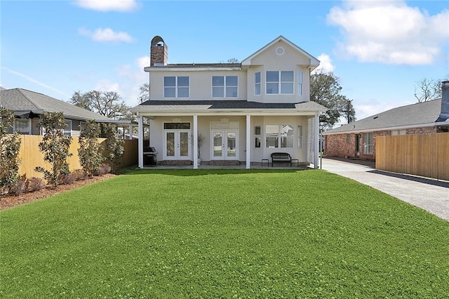 view of front of property with french doors, stucco siding, a front lawn, and fence