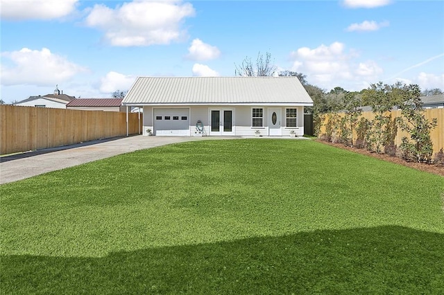 view of front of home featuring a front yard, concrete driveway, french doors, a garage, and metal roof