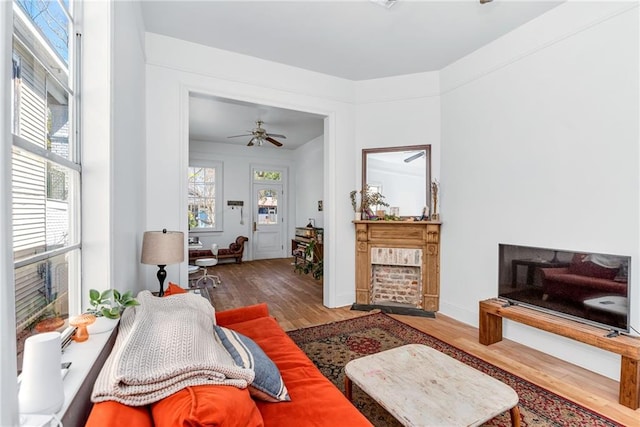 living area with a healthy amount of sunlight, a ceiling fan, and wood finished floors