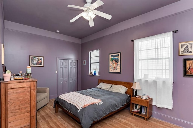 bedroom with a ceiling fan, baseboards, light wood-type flooring, and a closet