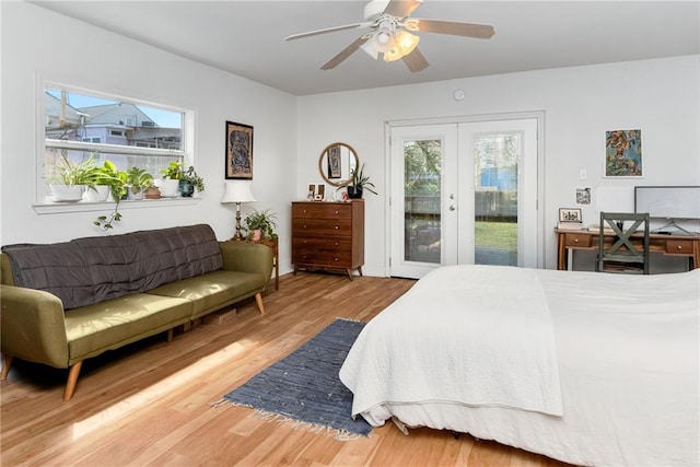 bedroom featuring access to exterior, multiple windows, wood finished floors, and french doors