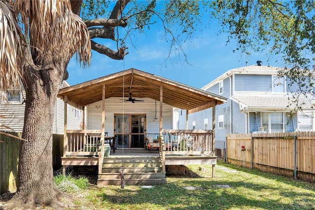 rear view of house with a lawn, a wooden deck, ceiling fan, and fence