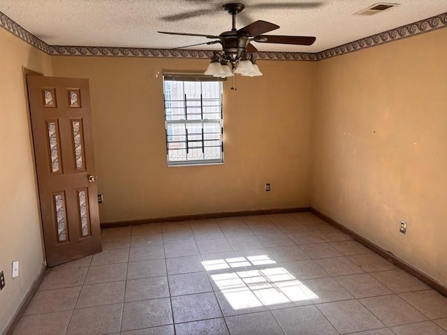 spare room with a textured ceiling, light tile patterned flooring, visible vents, and ceiling fan