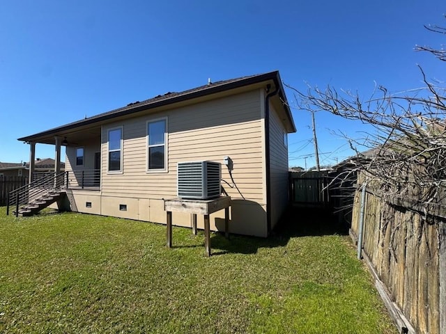 rear view of house featuring crawl space, a fenced backyard, central AC unit, and a yard