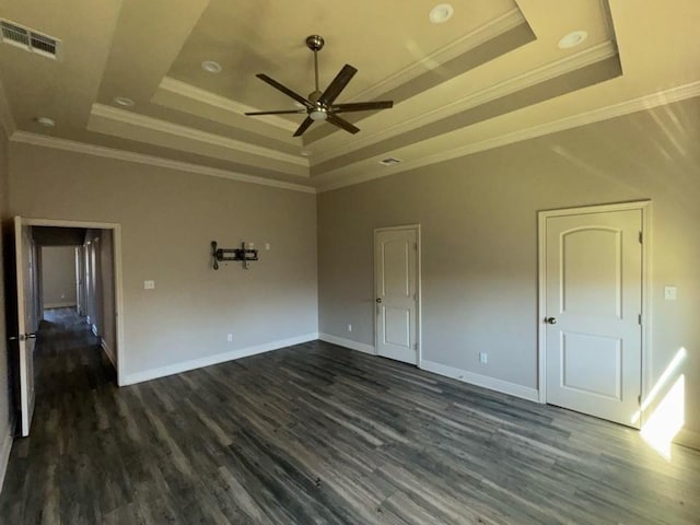 spare room with a tray ceiling, dark wood-style floors, and visible vents