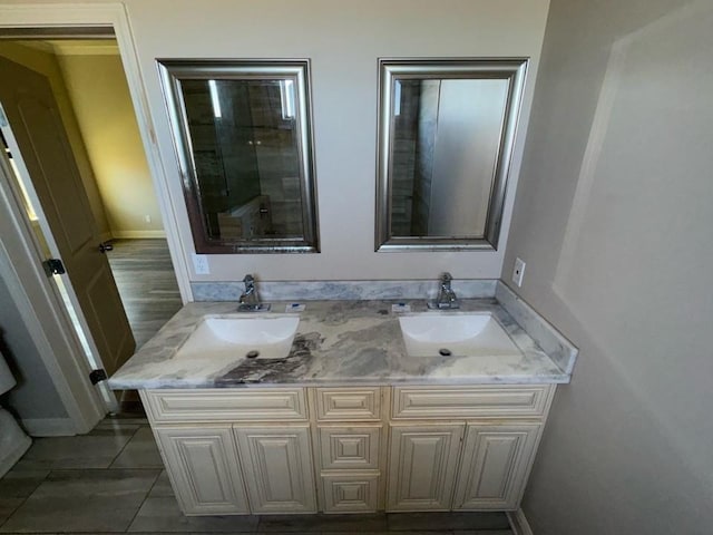 bathroom with double vanity, baseboards, and a sink