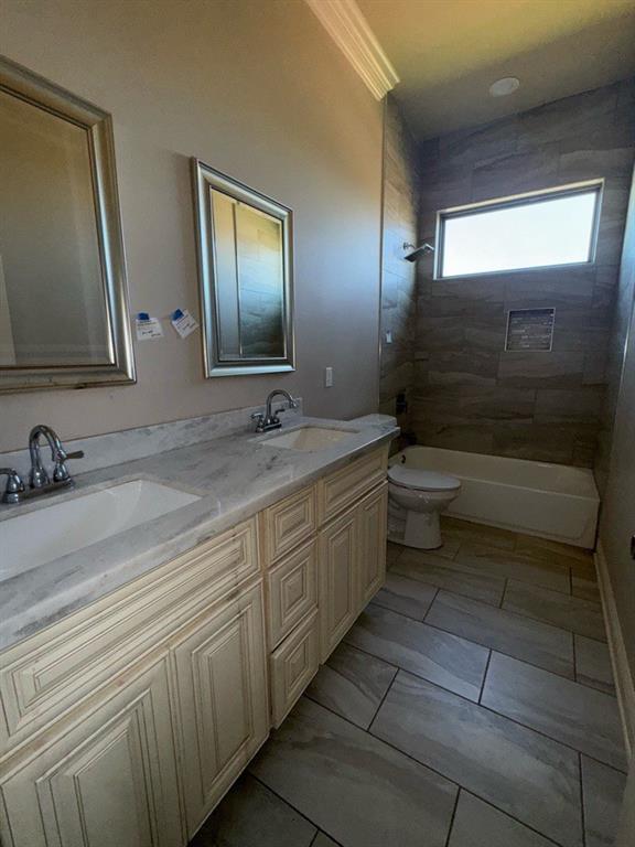 full bath with double vanity, toilet, shower / bath combination, and a sink