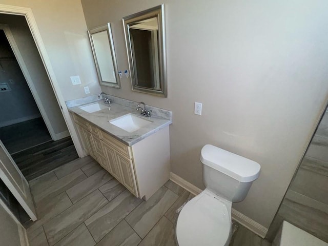 bathroom with a sink, baseboards, toilet, and wood tiled floor