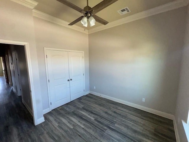 unfurnished bedroom featuring visible vents, baseboards, ornamental molding, a closet, and dark wood-style flooring