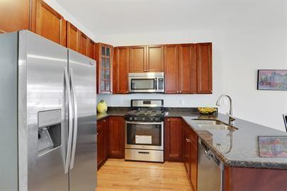 kitchen featuring dark stone counters, appliances with stainless steel finishes, a peninsula, light wood-style floors, and a sink