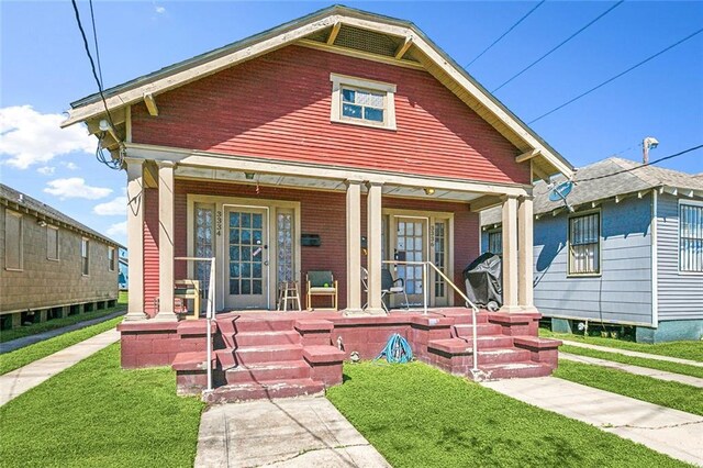 shotgun-style home with covered porch and a front lawn