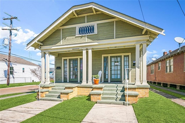 shotgun-style home with a porch and a front yard