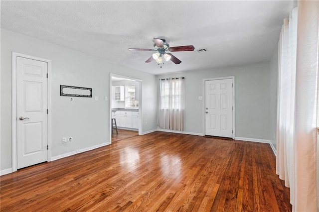 unfurnished living room featuring wood finished floors, a ceiling fan, and baseboards