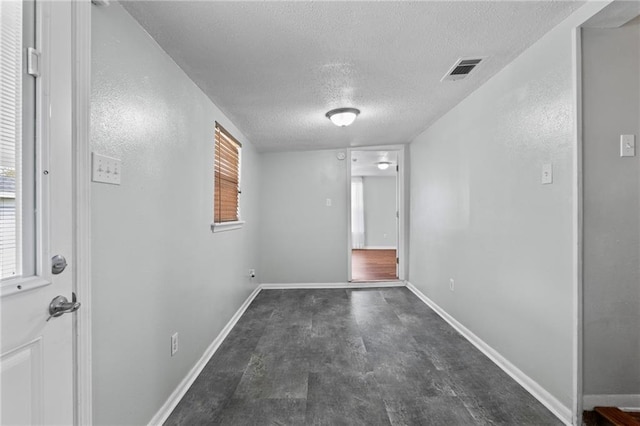 empty room with visible vents, baseboards, and a textured ceiling