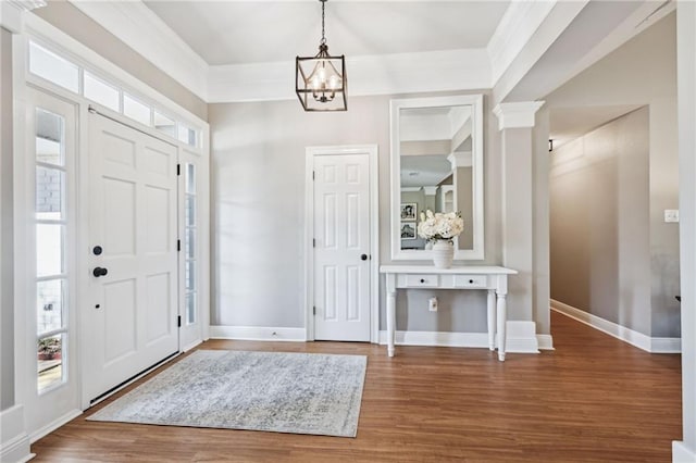 foyer entrance with baseboards, a notable chandelier, wood finished floors, and crown molding