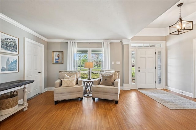 foyer featuring a notable chandelier, baseboards, light wood-style floors, and crown molding