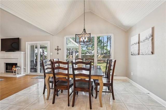 dining area featuring light tile patterned floors, plenty of natural light, a warm lit fireplace, and an inviting chandelier