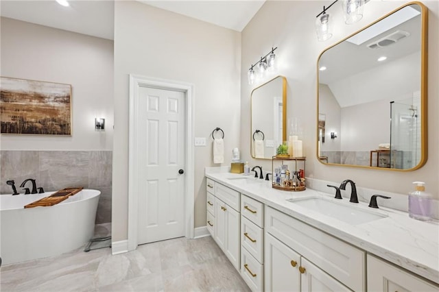 bathroom with double vanity, visible vents, a freestanding tub, and a sink