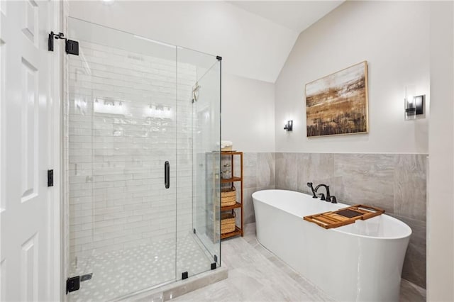 bathroom with a freestanding tub, lofted ceiling, tile walls, and a shower stall