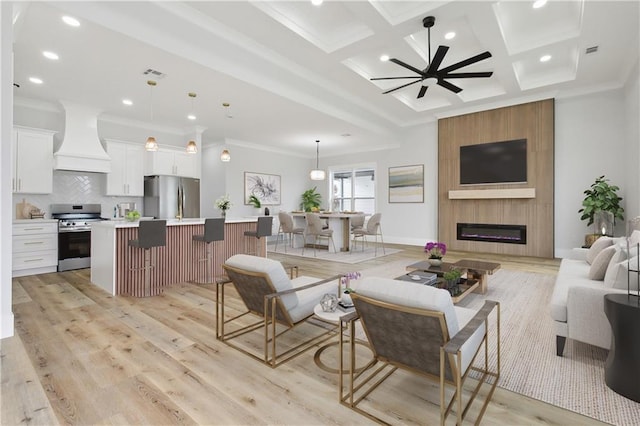 living room with crown molding, light wood finished floors, a ceiling fan, and coffered ceiling