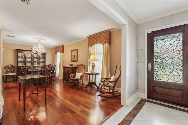 foyer entrance featuring baseboards, a notable chandelier, wood finished floors, and ornamental molding