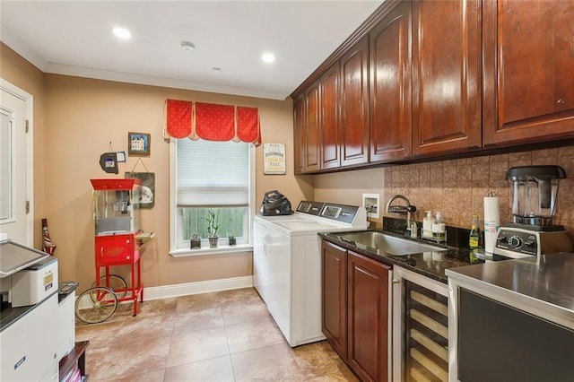 laundry area with crown molding, baseboards, washer and clothes dryer, wine cooler, and a sink