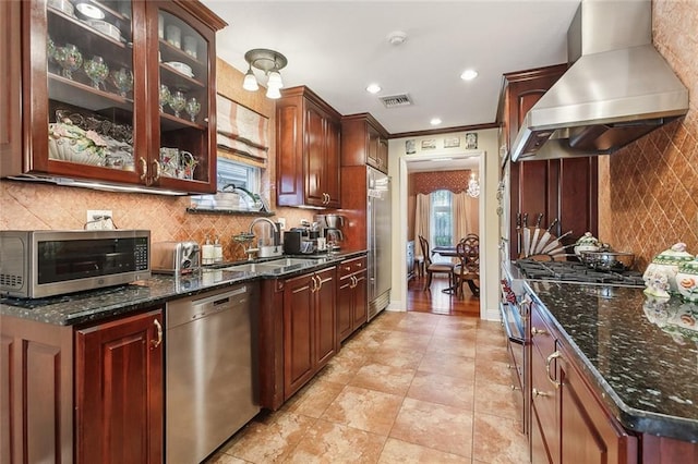 kitchen featuring visible vents, a sink, wall chimney range hood, high quality appliances, and backsplash