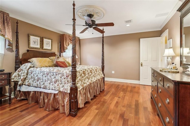 bedroom with visible vents, baseboards, light wood-style floors, and ornamental molding