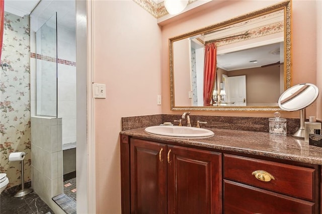 full bathroom with tiled shower, toilet, wallpapered walls, and vanity