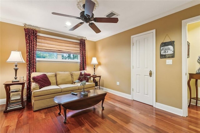 living area featuring visible vents, a ceiling fan, wood finished floors, crown molding, and baseboards