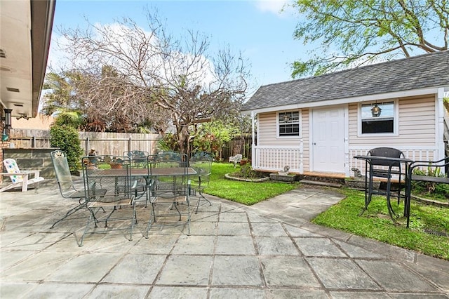 view of patio featuring an outdoor structure, outdoor dining area, and a fenced backyard