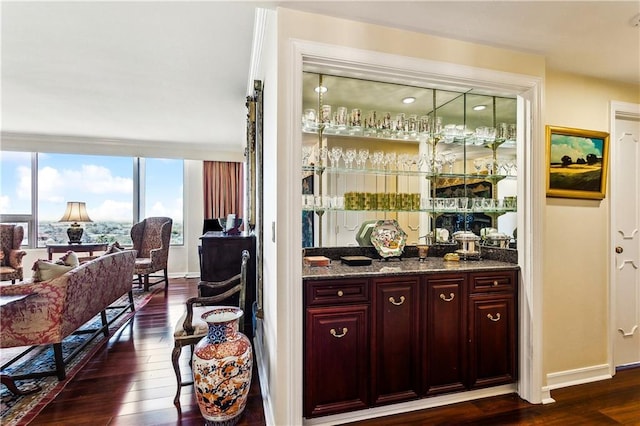 bar with baseboards, wet bar, and dark wood-style flooring