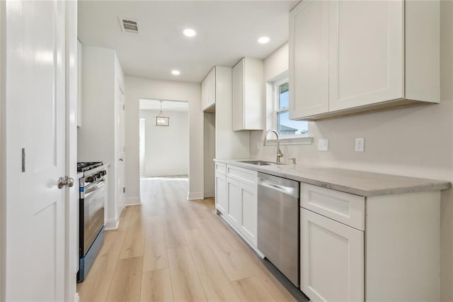 kitchen featuring visible vents, light wood-style flooring, a sink, white cabinetry, and stainless steel appliances