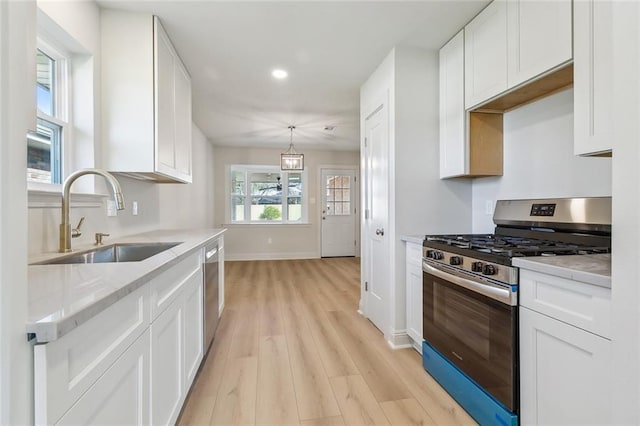 kitchen featuring appliances with stainless steel finishes, white cabinetry, and a sink