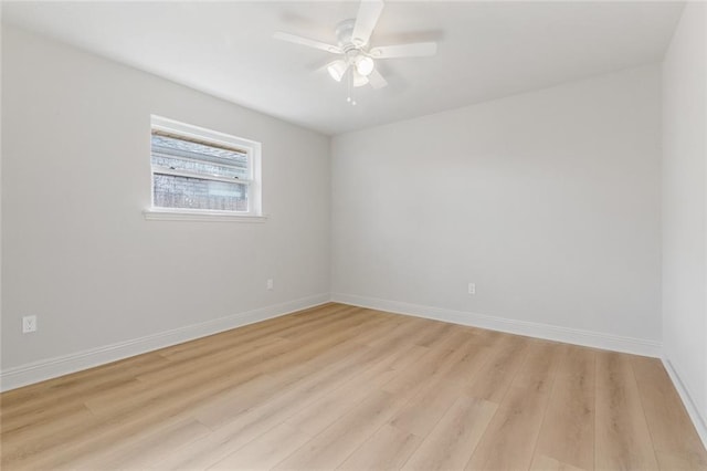 spare room featuring baseboards, light wood finished floors, and ceiling fan