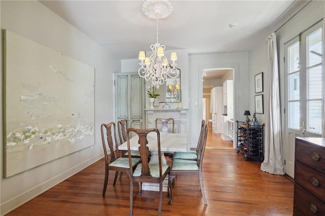 dining room with a chandelier, baseboards, and wood finished floors