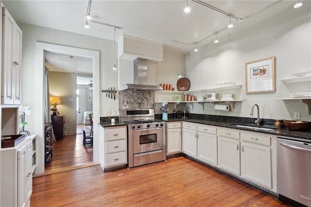 kitchen featuring open shelves, a sink, stainless steel appliances, wall chimney exhaust hood, and light wood-type flooring