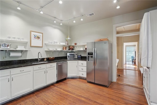 kitchen with visible vents, open shelves, a sink, stainless steel appliances, and light wood-style floors