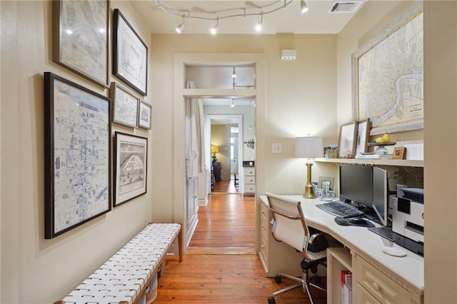 home office with visible vents, rail lighting, light wood-type flooring, and built in desk