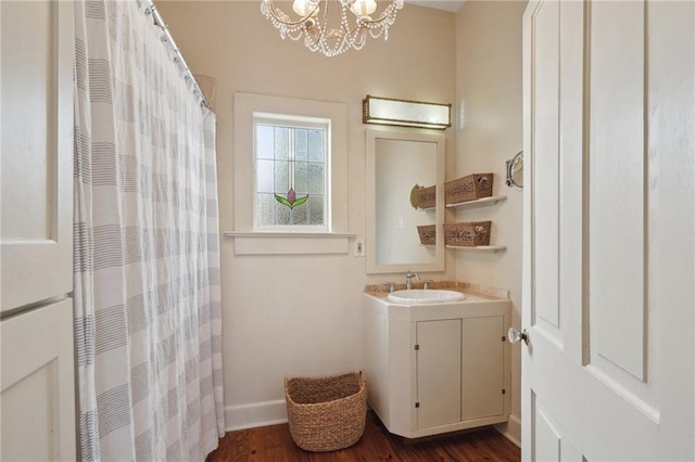 full bath featuring vanity, a shower with shower curtain, wood finished floors, baseboards, and a chandelier