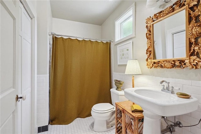 full bath featuring tile patterned floors, a wainscoted wall, toilet, a shower with curtain, and tile walls