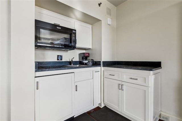 kitchen featuring dark countertops, visible vents, white cabinets, black appliances, and a sink