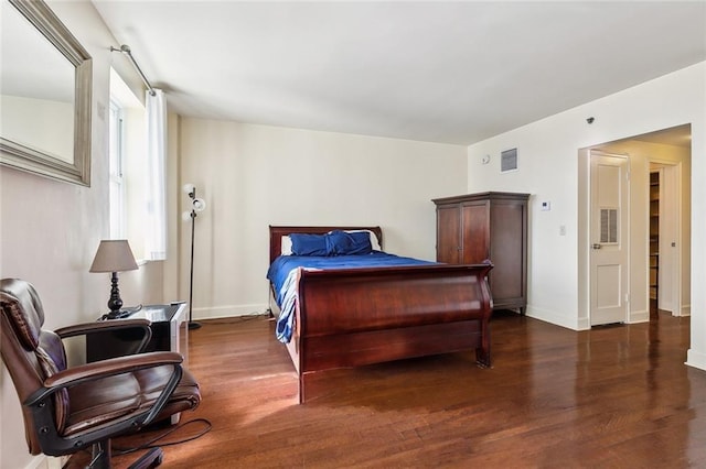 bedroom featuring visible vents, baseboards, and wood finished floors