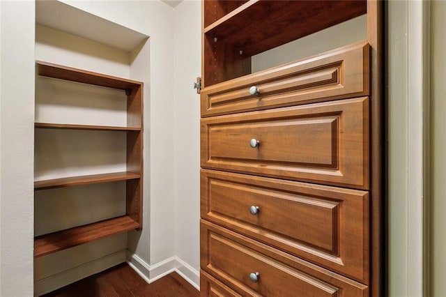 walk in closet with dark wood-type flooring